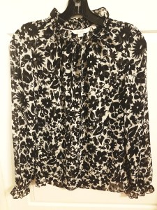 Sheer, floral, black and white blouse with ruflles. It has a self-tie neckline. By Boden.
